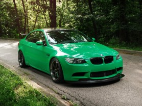 Green BMW M3 Coupe driving down the road
