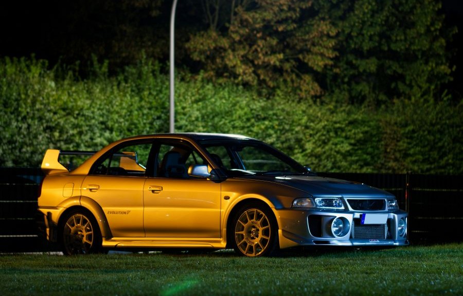 Evo parked outside under a street light with bushes in the background